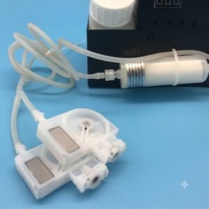 White Ink Circulation for A3 Printer India – Reliable Ink System - A close-up view of two white plastic peristaltic pump heads in the foreground connected by flexible clear tubing to a white inline cylindrical filter and a black control box on a light blue background.