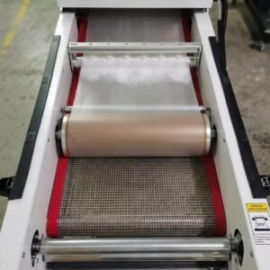 DTF Audley Dual Head I3200 Printer 12 inch with Powder Shaker – High-Precision Mid-Range DTF Printer | ProlificGeeks - Top-down view of a DTF powder shaker showing a stainless steel wire mesh conveyor belt with red borders and feed rollers inside a heating tunnel.