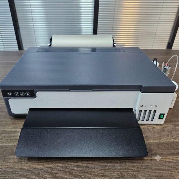 A3 DTF L18050 Printer with Module โ Powerful & Compact DTF Printing Machine | ProlificGeeks - Front view of a compact desktop DTF transfer printer with an extended output tray, roll feeder, and ink windows on a wooden desk.